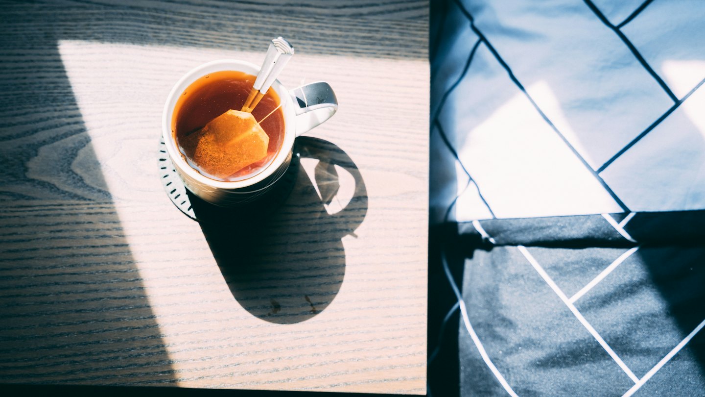 A white mug of tea sits on a wooden table.
